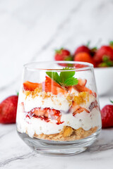 Italian strawberry tiramisu dessert with mascarpone and whipped cream, savoyardi crumb and fresh strawberry in glass on marble. Recipe of simple dessert, cheesecake, pudding or berry trifle cake.