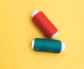 red and dark Cyan color yarn or spool thread over on yellow background
