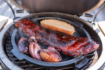 smoking spareribs and red onions on a ceramic grill with charcoal