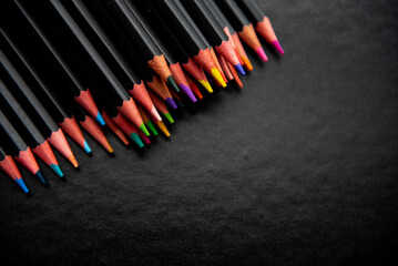 Crayons de couleur sur un fond noir avec de l'espace vide - coloriage et créativité