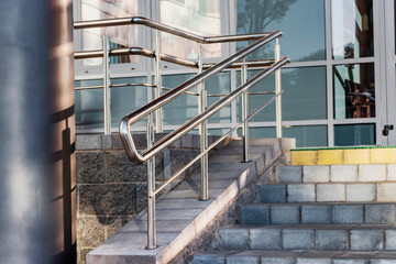 A ramp and metal railings at the entrance to the residential building for the convenience of people with disabilities and the elderly.