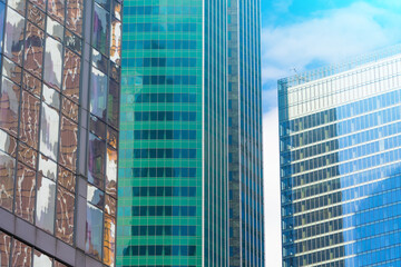 Fototapeta na wymiar Angle glass red, burgundy, brown, green, aqua clolrs facades of a window of financial skyscrapers, a corner of a building close-up.