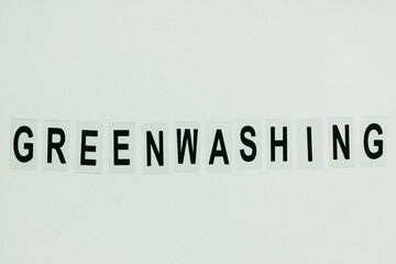 Text GREENWASHING on green background. Green PR, green marketing and misleading information about company products being eco-friendly concept