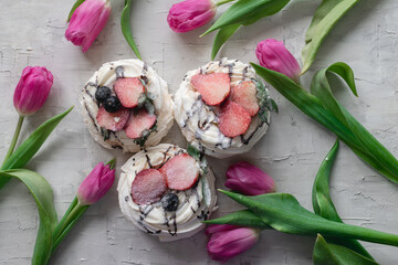 Cake next to flowers on a gray background. Confectionery. Sweet dessert. Meringue cake. Card. Advertising. Layout of confectionery. Spring background.