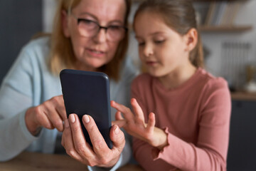 Caucasian grandmother and her granddaughter using smart phone together