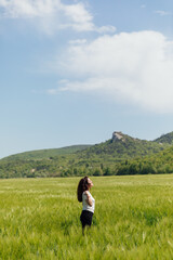 Fototapeta na wymiar woman traveler in the field looks at the beautiful landscape