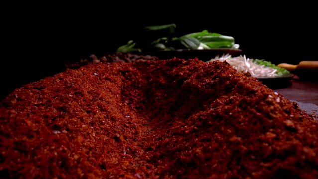 Slow-motion red chili powder tracking in shot in a studio with black background.