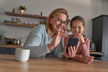 Caucasian grandmother and her granddaughter using smart phone together