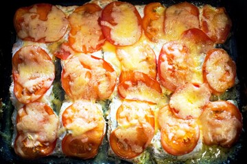 A dish of red salmon fish cooked in a large pan with tomatoes and cheese and emits mouth-watering aromas