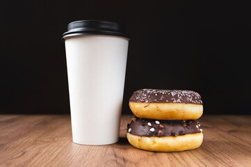 white coffee cup on dark wooden background with donuts
