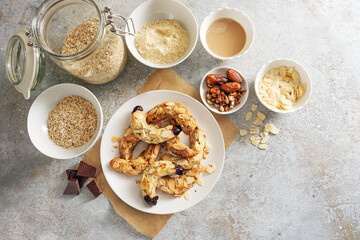 Healthy almond crescent cookies without sugar made from almonds, oat flakes and dates on a plate and ingredient on a rustic gray background, baking at home concept, copy space, top view from above