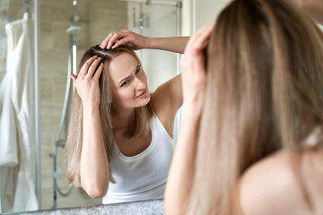 Caucasian woman checking hair condition in the bathroom