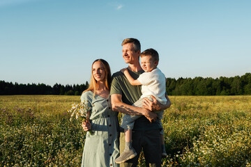 Mother, father and son squint from the sun in the field