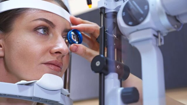 Beautiful woman at ophthalmologist's examination. Doctor's hand holds a tool close to the patient's eye. Close up.