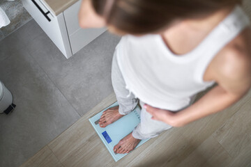 Top view of caucasian woman standing on bathroom scale