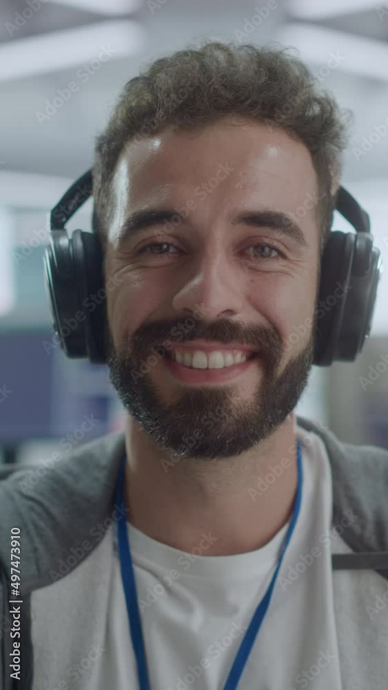 Poster vertical screen. office: portrait of it programmer wearing headphones working on computer, looking a