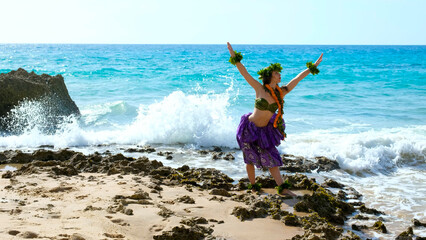 Woman rests and poses happily on the beach wearing the typical hula dance costume. Hawaiian dance...