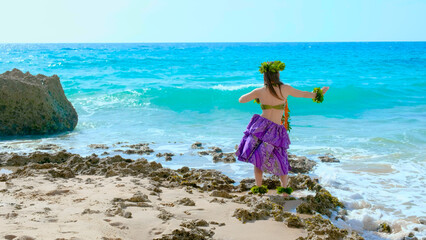 Woman rests and poses happily on the beach wearing the typical hula dance costume. Hawaiian dance...