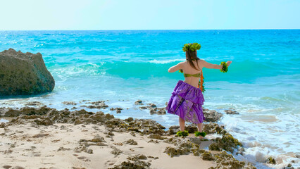 Woman rests and poses happily on the beach wearing the typical hula dance costume. Hawaiian dance beauty. Exotic girl.