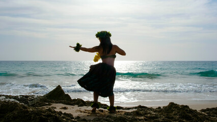 Woman rests and poses happily on the beach wearing the typical hula dance costume. Hawaiian dance beauty. Exotic girl. Silhouette of woman dancing hula. - obrazy, fototapety, plakaty