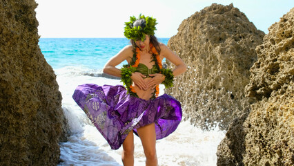 Woman rests and poses happily on the beach wearing the typical hula dance costume. Hawaiian dance beauty. Exotic girl.
