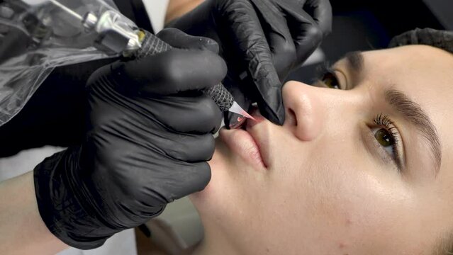 A cosmetologist applies permanent makeup to the lips in a beauty salon. Tattoo