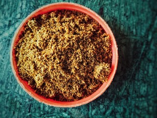 Wet tobacco in red bowl on green background