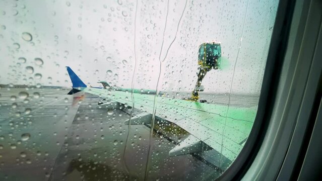 Window Seat POV As Airplane Has Wing Sprayed With Green De-Icing Fluid