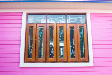wooden windows and glass and the pink walls of the house are plasterwood that is popularly used to build houses these days. It is a modern style house and is becoming popular to replace the real wood.