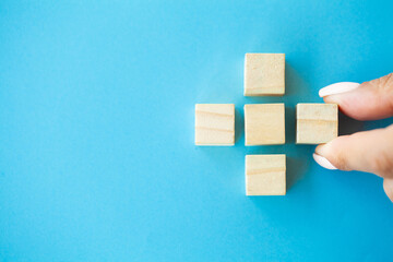 Business concept, hand places wooden cubes on blue background
