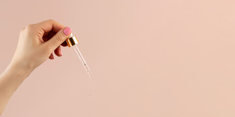 A drop of serum for the skin flows down from the pipette, which lies on the stone. 