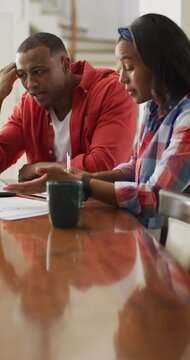 Vertical video of stressed african american couple discussing finances in living room