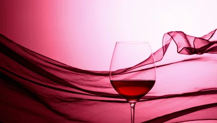 Rolgordijnen Glass of red wine on a background of waving curtain. © Igor Normann