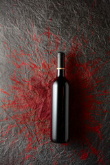 Bottle of red wine on a paper background with stains of wine.