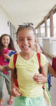 Vertical video of portrait of happy diverse schoolgirls embracing at school