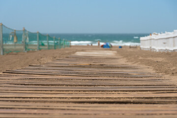 Selective focus of a wooden path on the beach with the sea in the background