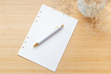 Flat lay, top view of blank, lined paper, flower bouquet and stationery on a wooden surface. Minimalistic workspace, creative writing, blogging, planning, business.