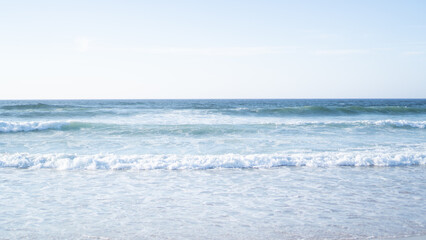 Fototapeta na wymiar Algarve ocean waves. Small coast waves. Sea foam lines. Abstract sea background. Blue ocean backdrop