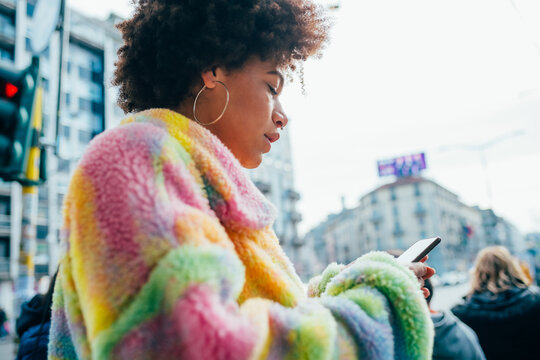 Young black curly hair woman outdoor using smartphone surfing web