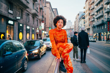 Cool young black woman afro curly hairstyle posing outdoor looking camera