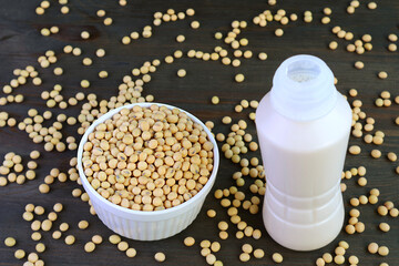 Bottle of Soy Milk Isolated on Black Wooden Table with Scattered Soy Beans
