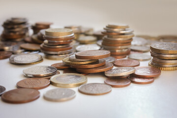 Scattered coins of different countries and stacks of coins with selective focus, side view