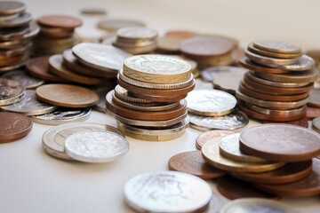 Scattered coins of different countries and stacks of coins with selective focus