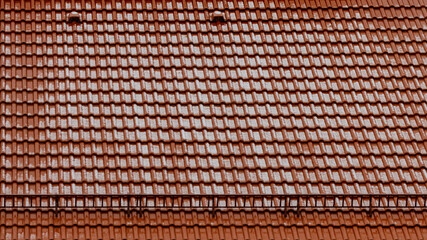 Close-up view of the roof of the house of orange tiles dusted with spring snow