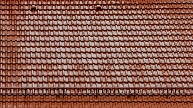 Close-up view of the roof of the house of orange tiles dusted with spring snow