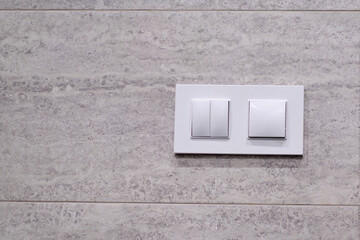 light switch, a white plastic mechanical switch mounted on a ceramic tile wall