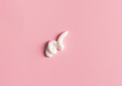 Smear Of White Face Cream On Pink Background. Cosmetic Product Texture