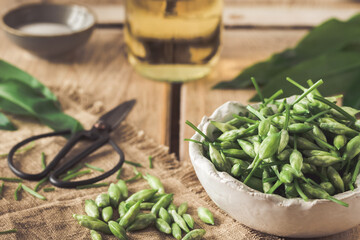 Wild garlic buds and leaves, salt and vinegar on a rustic wooden background