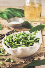 Wild garlic buds and leaves, salt and vinegar on a rustic wooden background