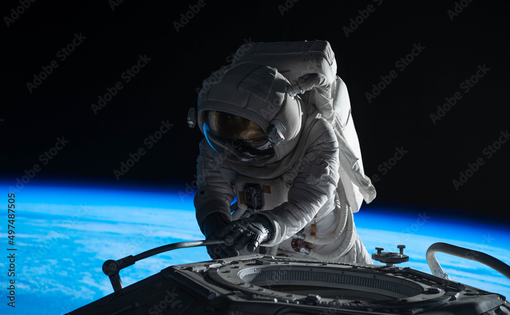 Wall mural female astronaut performing spacewalk, working on a outer part of a space craft